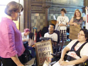 Maria Miller, Minister for Disabled People, is questioned by protesters.